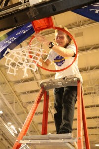 Barton College Women's Basketball Coach Wendee Saintsing cutting down the net at a Championship game.